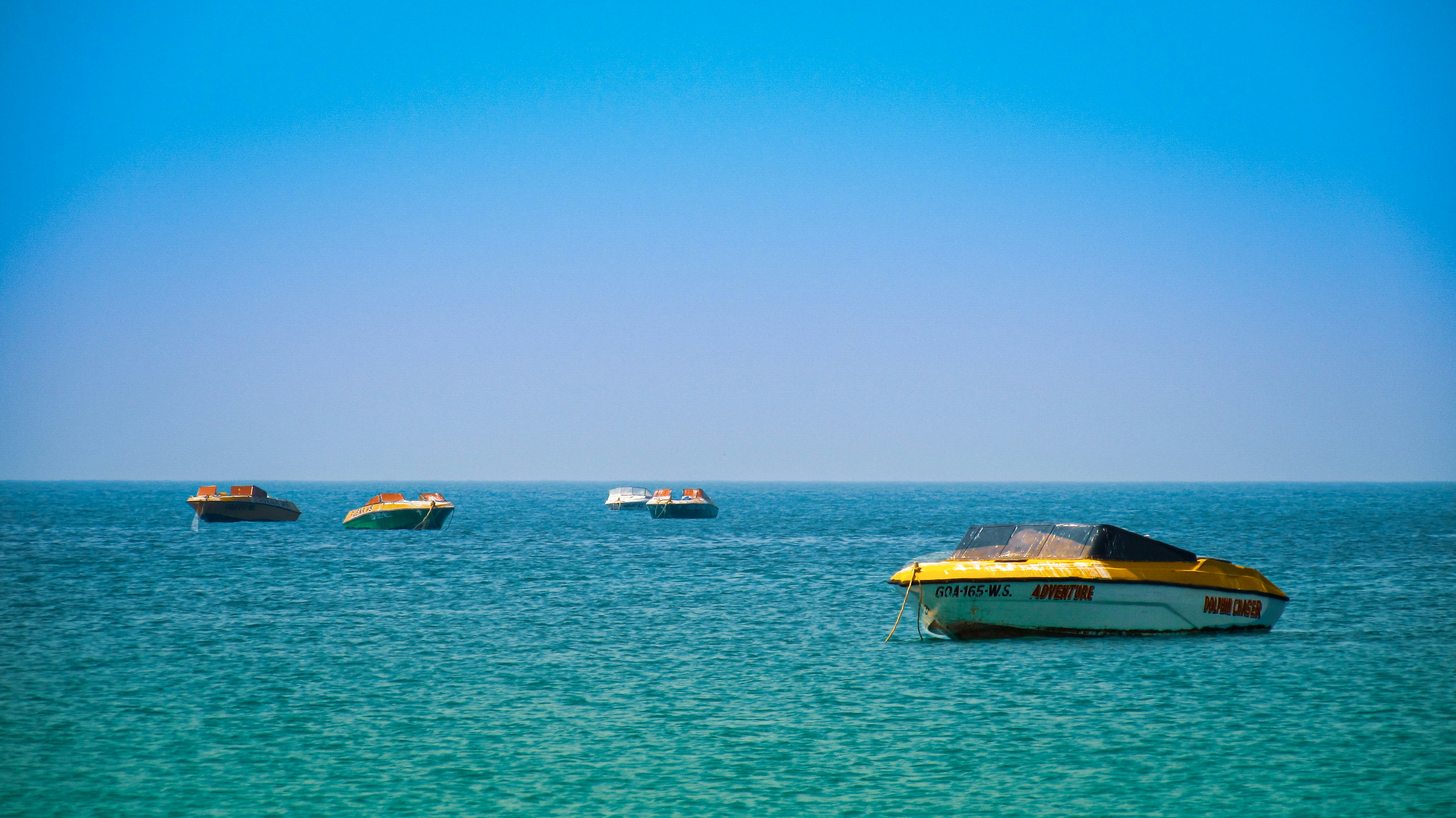 brown and white boat on sea under blue sky during daytime,goa