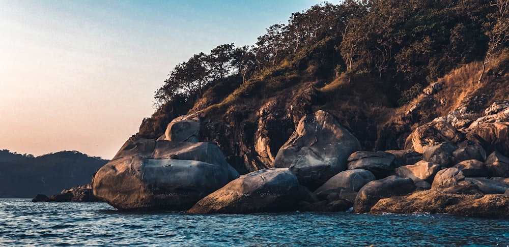 brown rocky mountain beside body of water during daytime