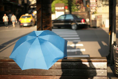 A compact umbrella folded neatly, resting inside a stylish handbag on a city bench.