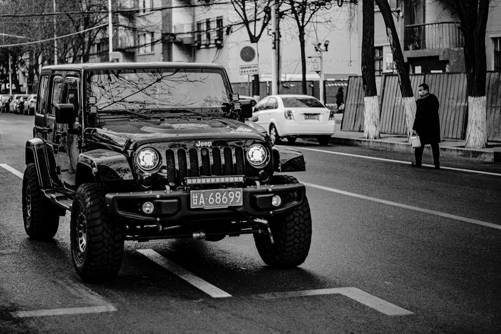 grayscale photo of jeep wrangler on road