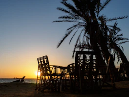 brown wooden chairs on beach during sunset