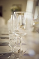 A set of elegant wine glasses with personalized etched initials on a rustic wooden table.