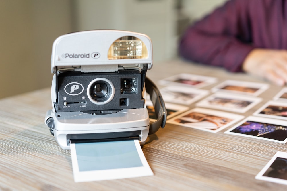 White and black polaroid camera on brown wooden table photo – Free Tiel  Image on Unsplash