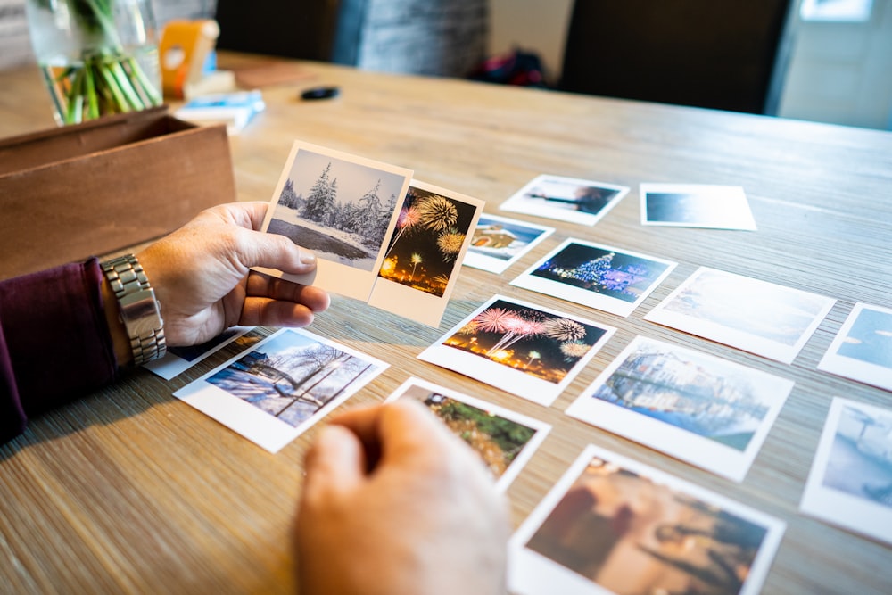person holding photos on brown wooden table