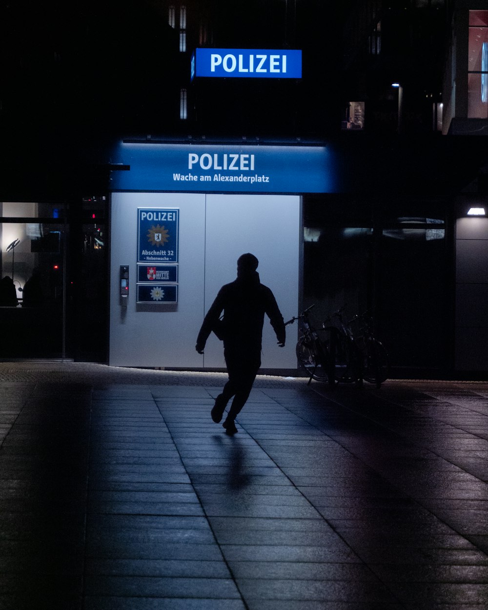 man walking on sidewalk during night time