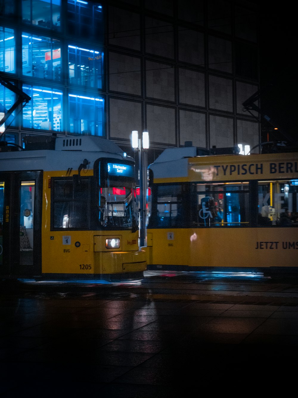 a yellow bus driving down a street next to a tall building