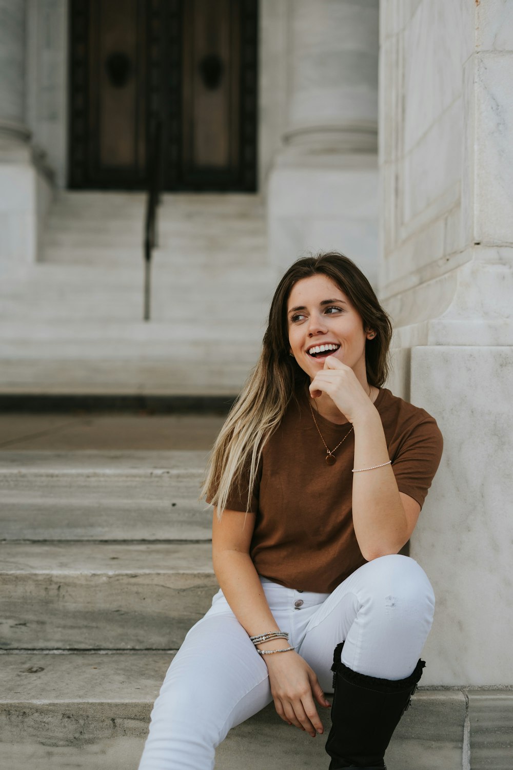 woman in brown shirt and white pants sitting on concrete stairs