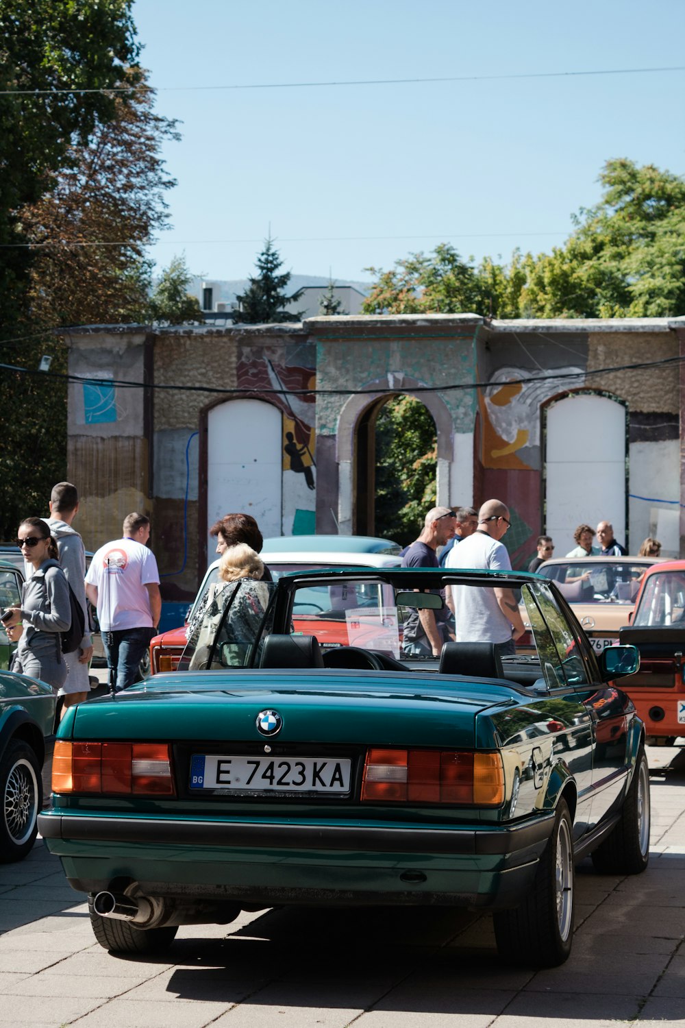 people standing beside red and black car during daytime