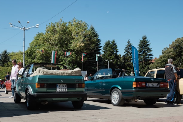 A friendly car buyer inspecting various cars in a sunny outdoor lot.