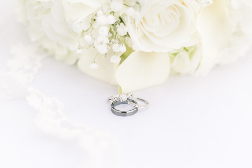 anello di diamanti in argento accanto a rosa bianca