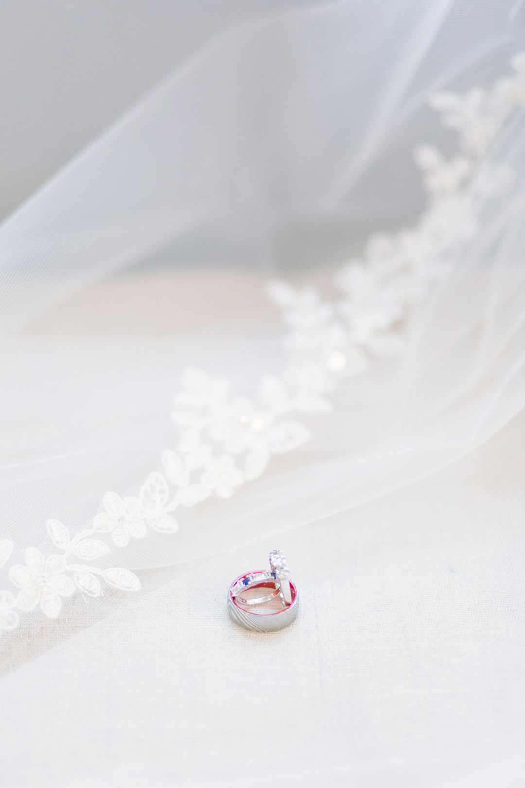 silver and red diamond ring on white textile