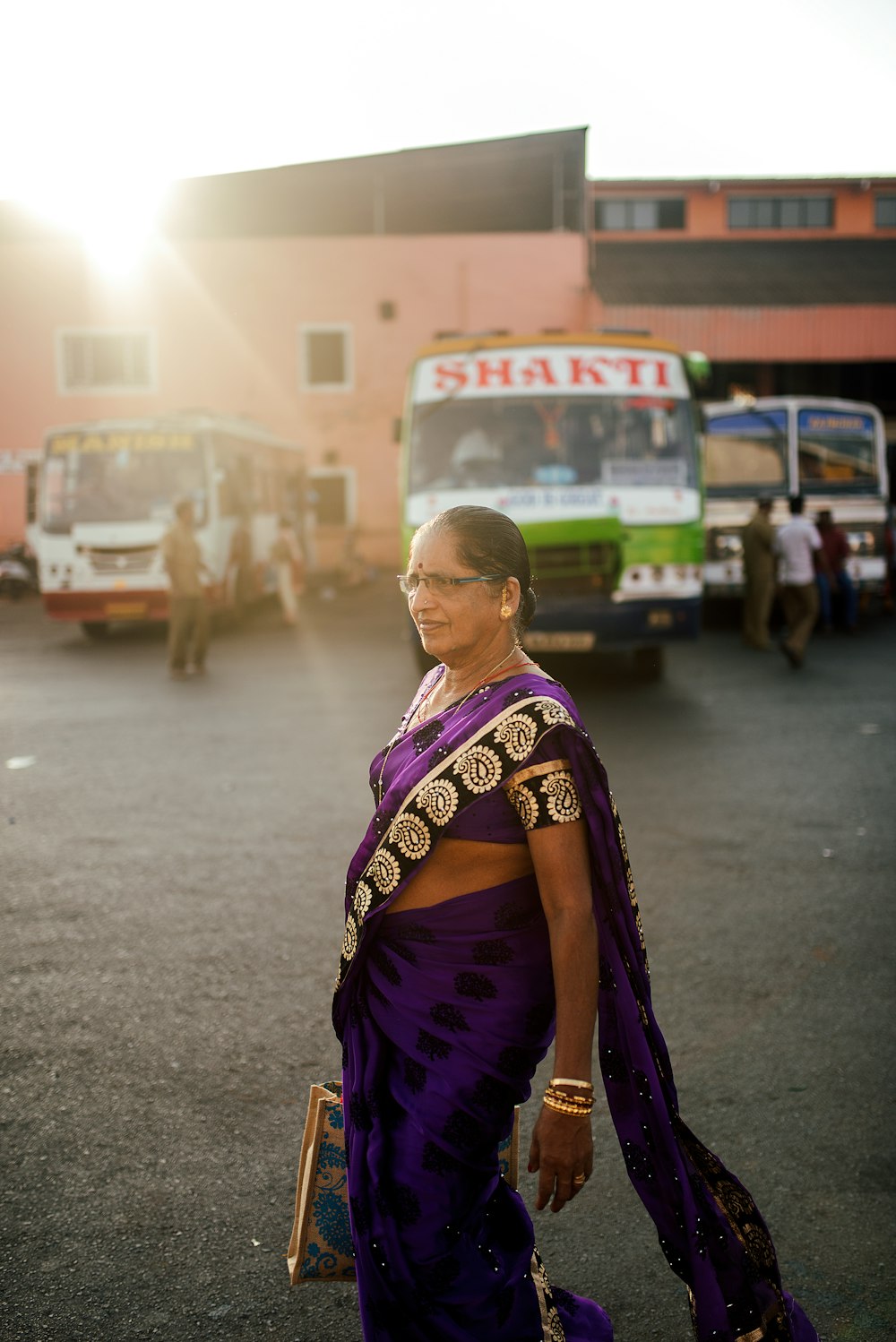 woman in purple and yellow sari standing on road during daytime