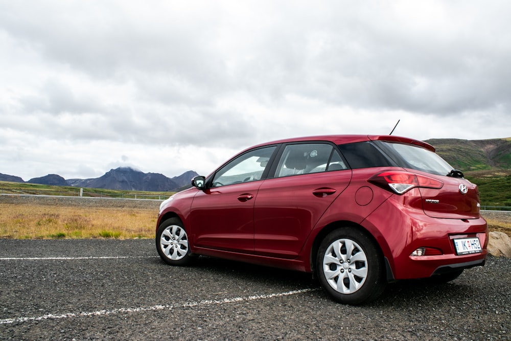 red 5 door hatchback on gray asphalt road during daytime