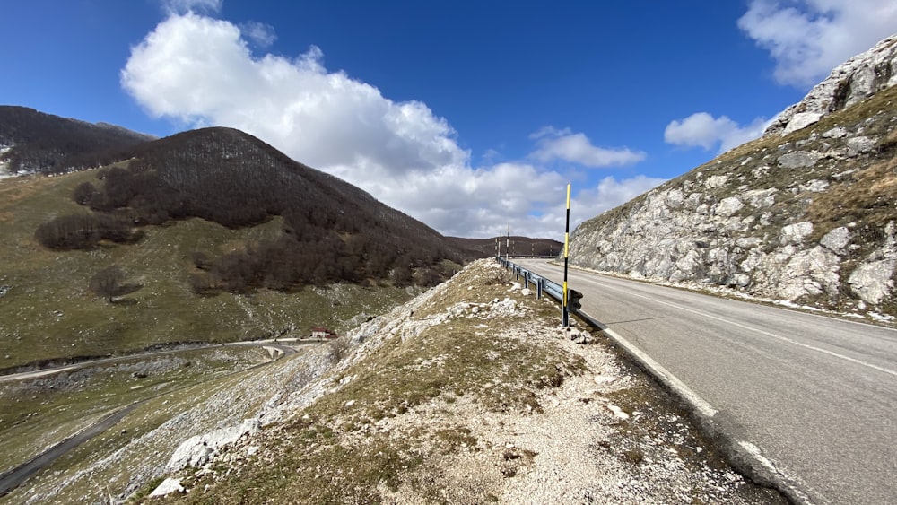 gray concrete road near mountain under blue sky during daytime