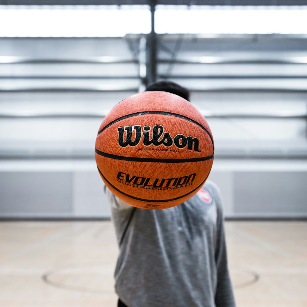 person holding brown basketball ball