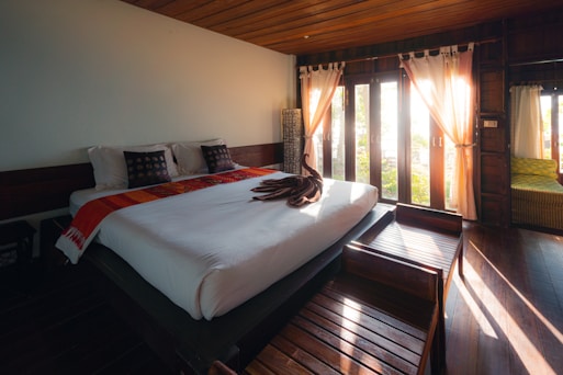white bed linen near brown window curtain