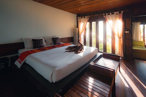 white bed linen near brown window curtain