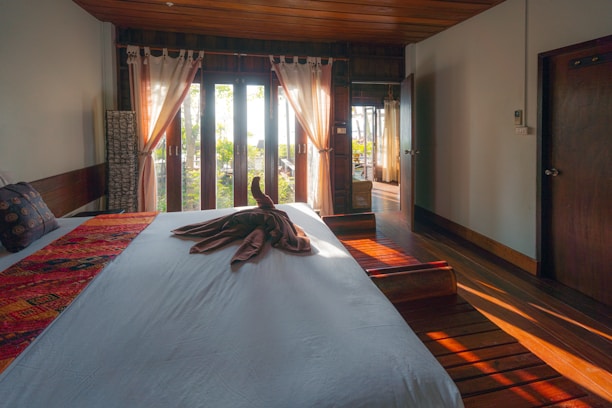 white bed cover on brown wooden parquet floor