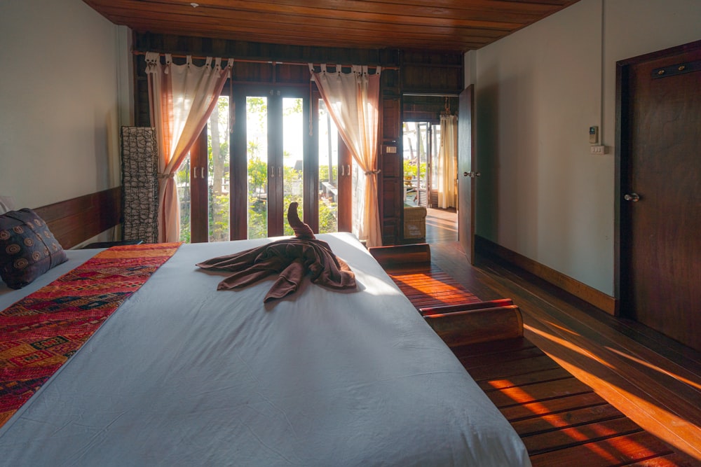 white bed cover on brown wooden parquet floor