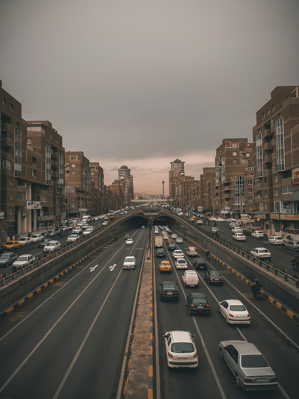 cars on road between high rise buildings during daytime