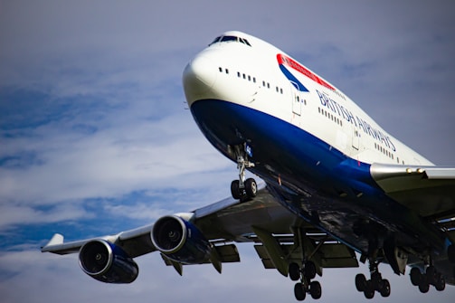 white and blue airplane under white clouds during daytime