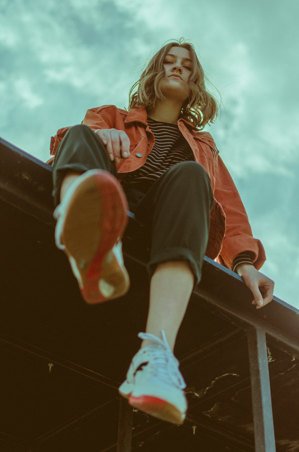 girl in red and black stripe long sleeve shirt and black pants sitting on black metal