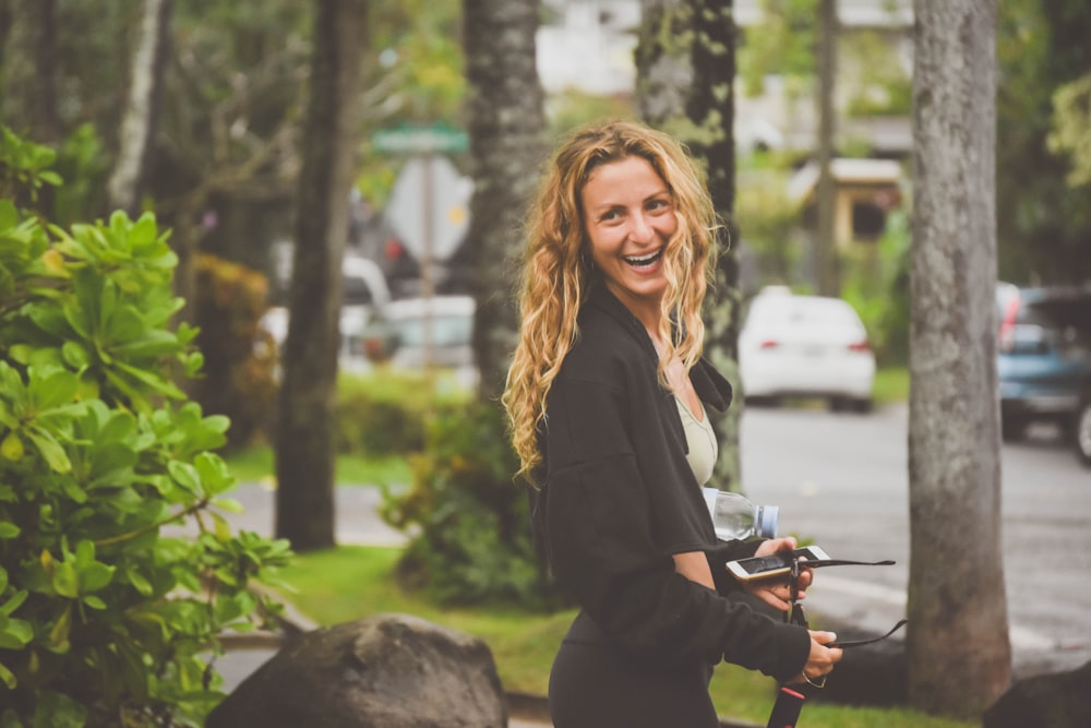 mulher no blazer preto que segura a bicicleta