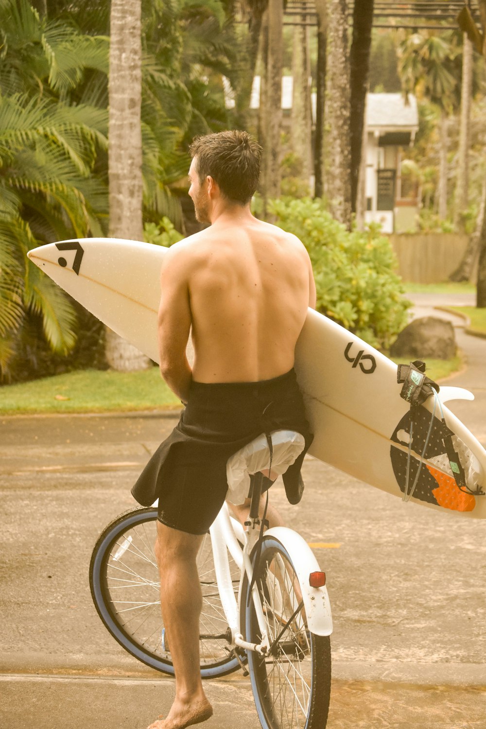 topless man in black shorts riding white and black bicycle during daytime