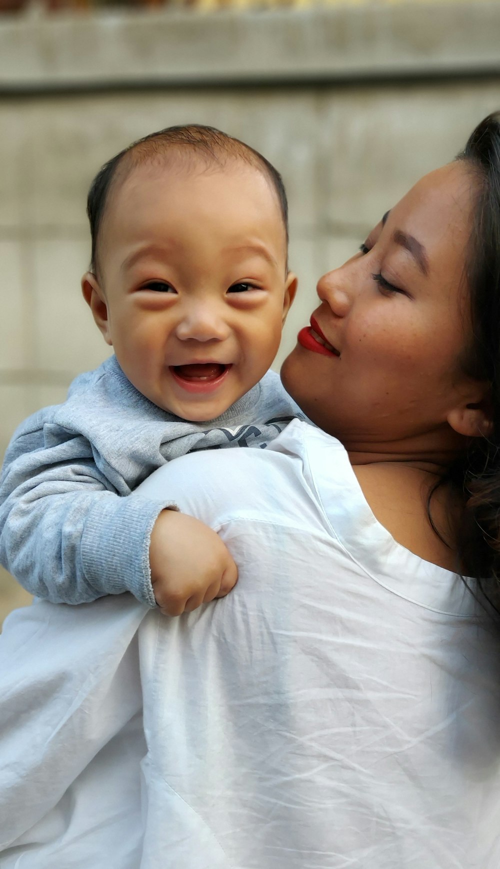 woman in white shirt carrying baby in blue long sleeve shirt