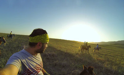 A group enjoying a peaceful trail ride through lush green fields at sunset.