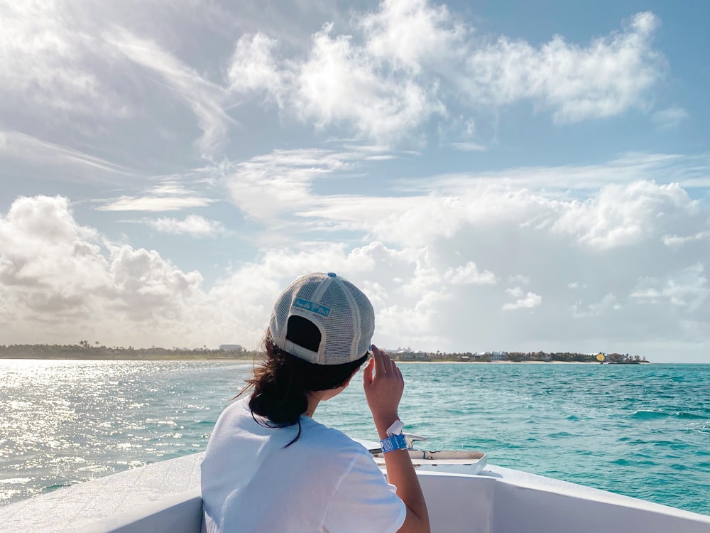 woman in white shirt wearing white helmet sitting on white boat during daytime