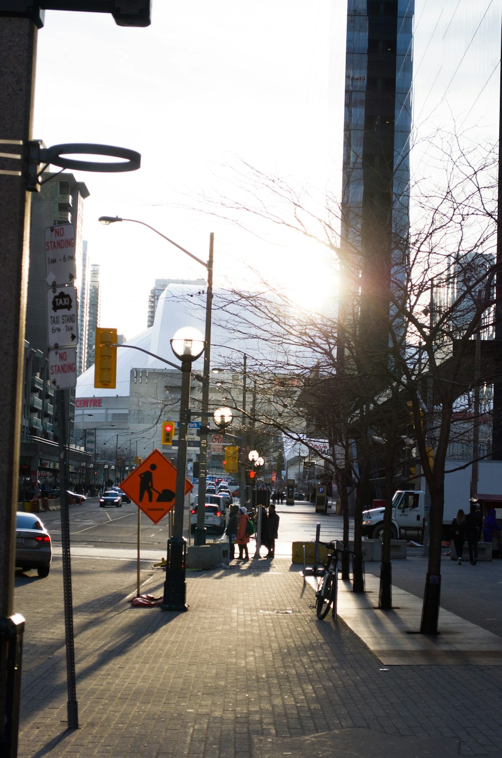 people walking on sidewalk near street light during daytime