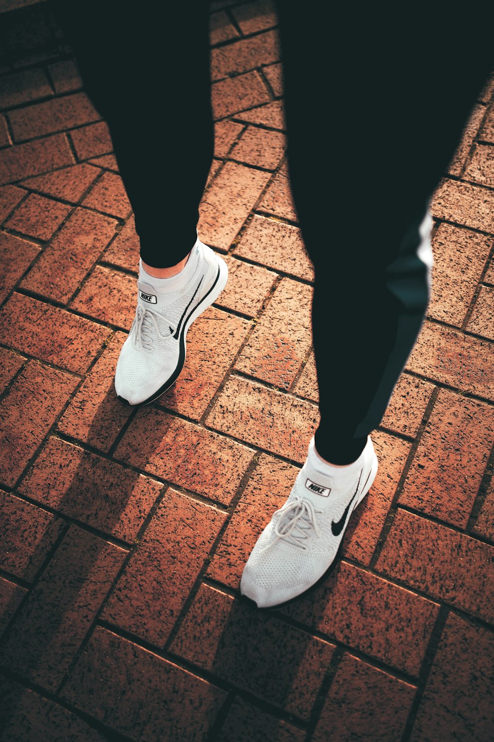 person in black pants and white nike sneakers