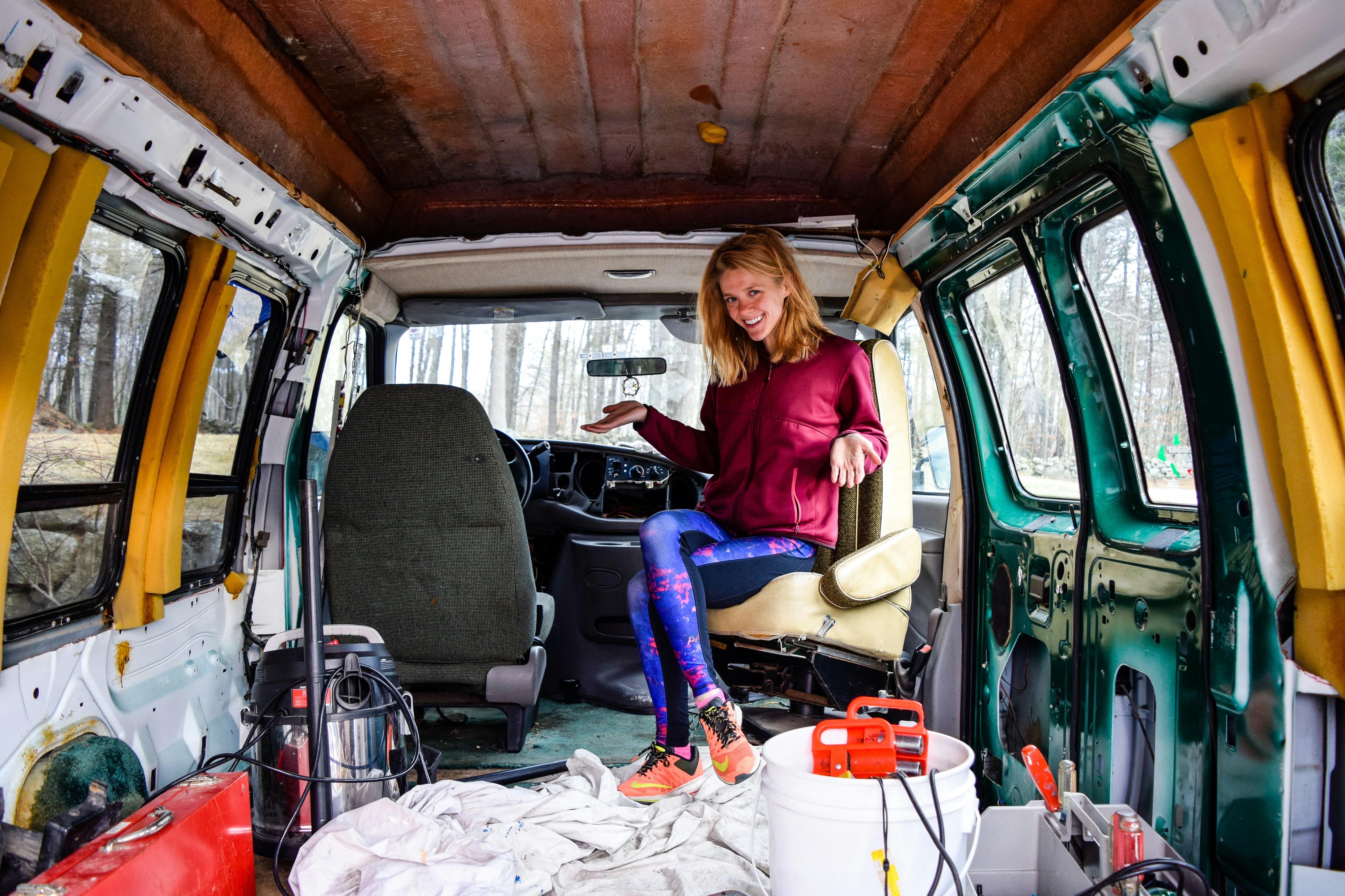 woman in red long sleeve shirt and blue denim jeans sitting on green van new hampshire teams background