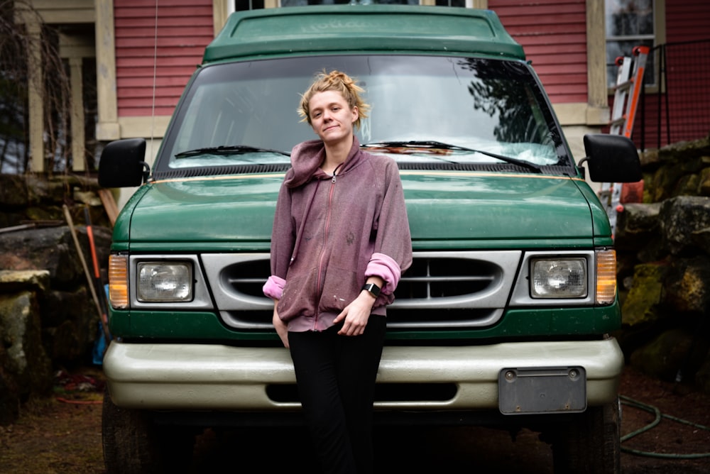 woman in pink sweater standing beside green car