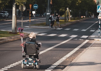 girl riding in a black and gray wheelchair in the bike lane