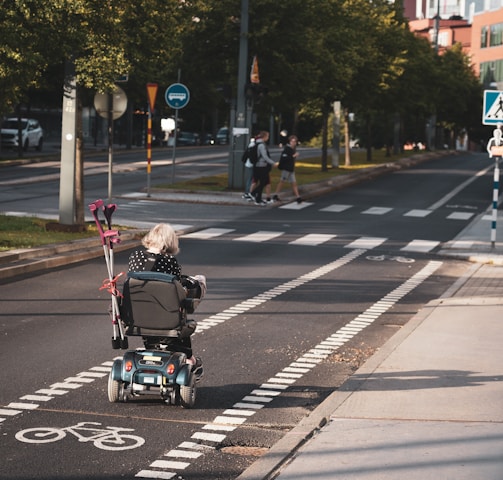 girl riding in a black and gray wheelchair in the bike lane