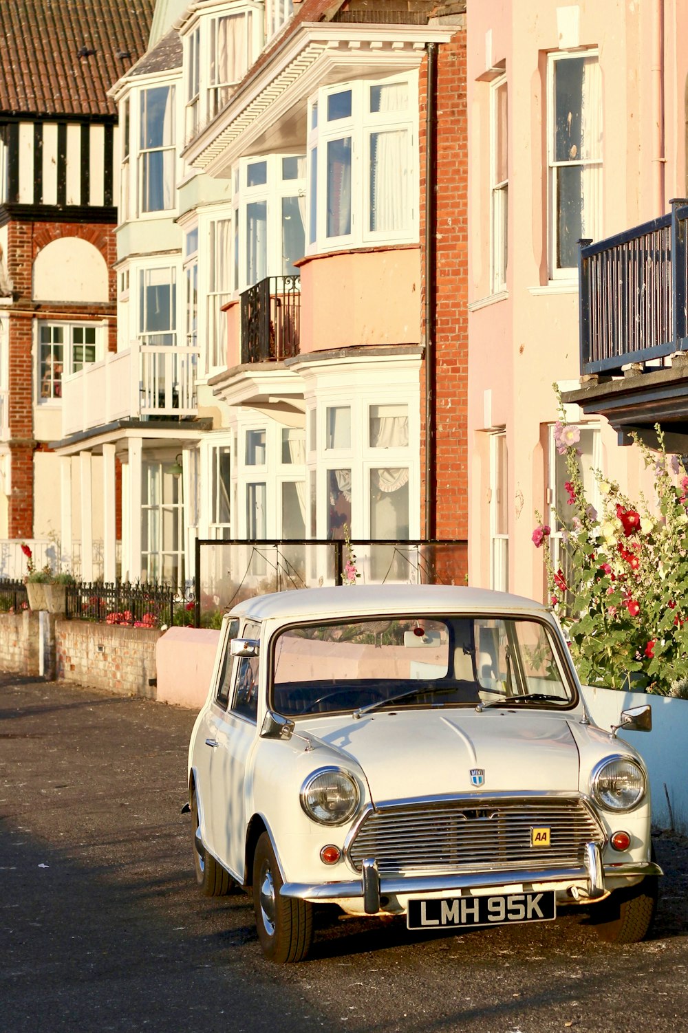 white classic car parked beside white and brown concrete building during daytime