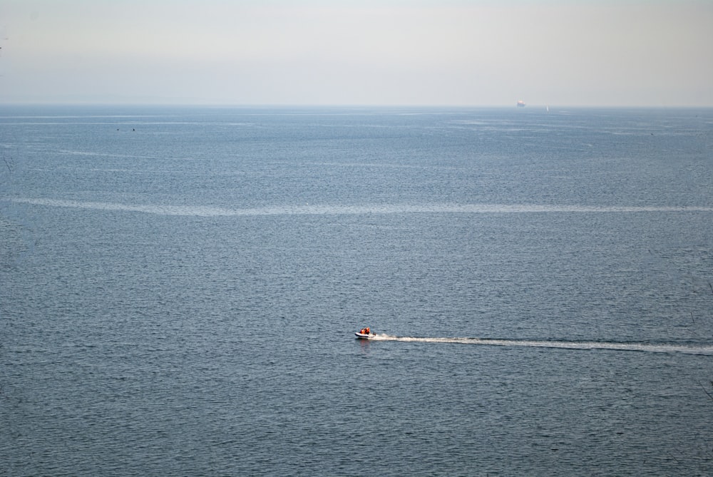 person in red shirt riding on white boat on blue sea during daytime