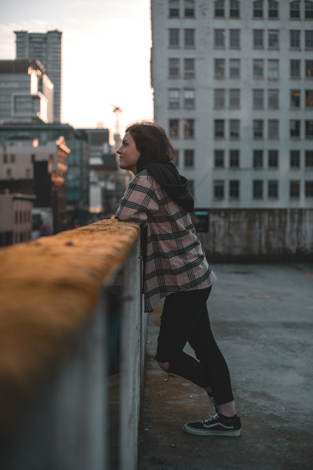 woman in black and white scarf leaning on gray metal railings during daytime