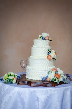 Elegant wedding cake with white fondant and fresh flower decorations on a rustic wooden table.