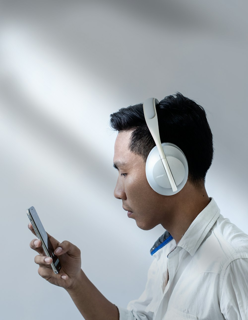 man in white dress shirt holding smartphone