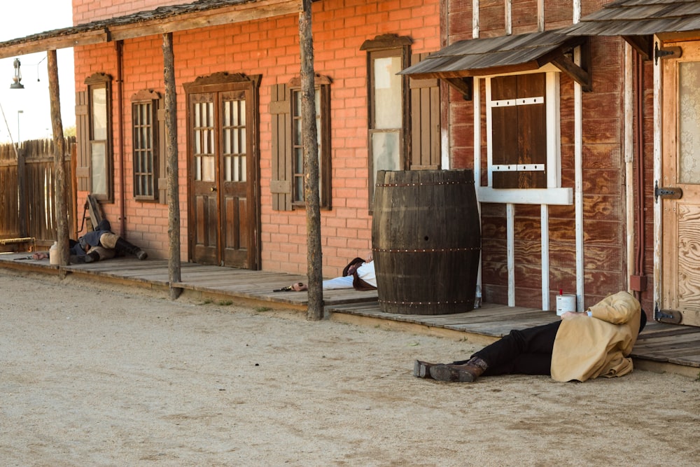 person in black pants and black boots sitting on brown wooden barrel