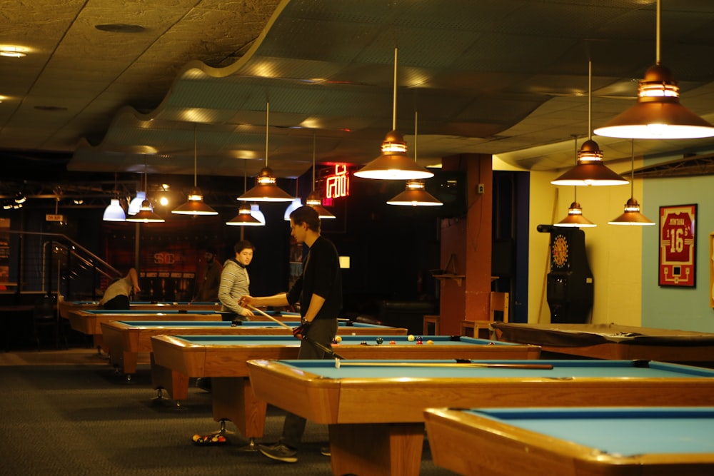man in black shirt and brown hat standing near pool table