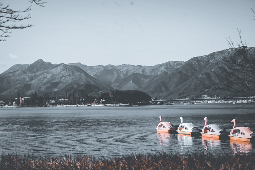 낮 동안 산 근처 물에 흰색과 주황색 풍선 보트