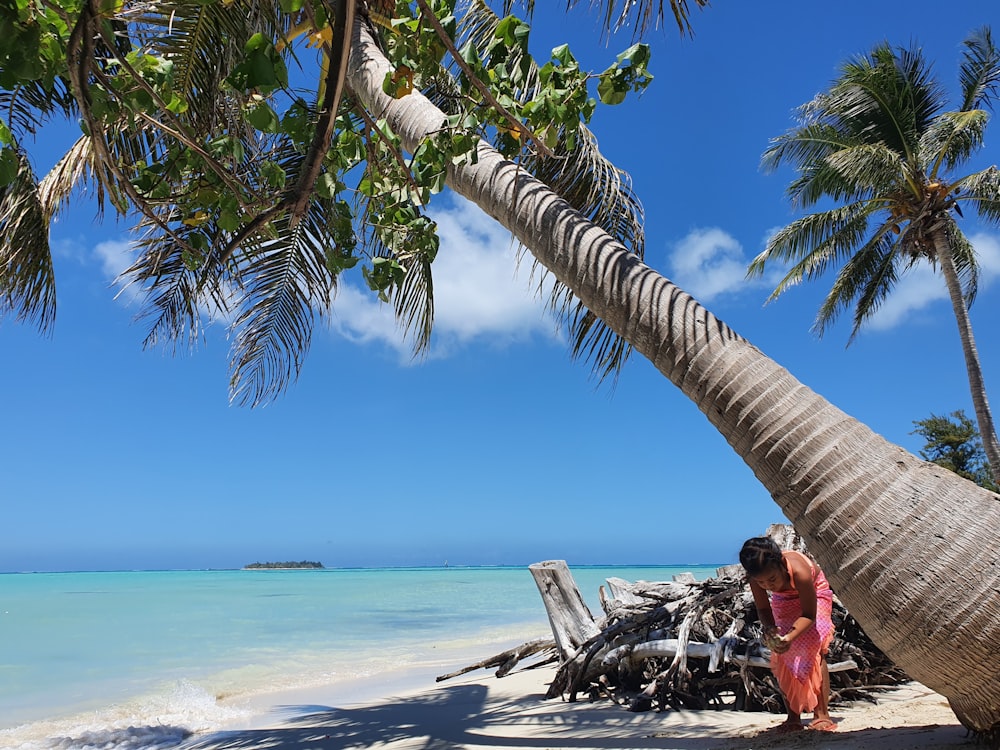 femme en robe rouge assise sur hamac près de la plage pendant la journée