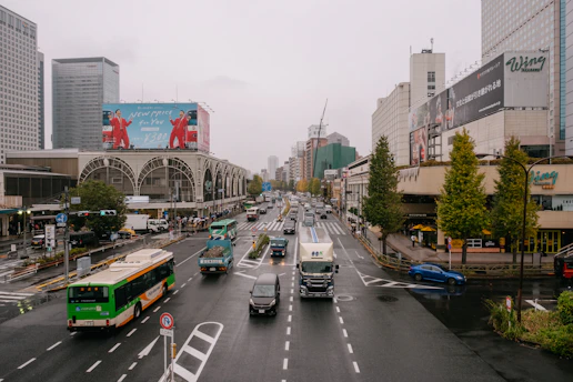 A busy urban street scene with multiple cars featuring colorful advertisements.
