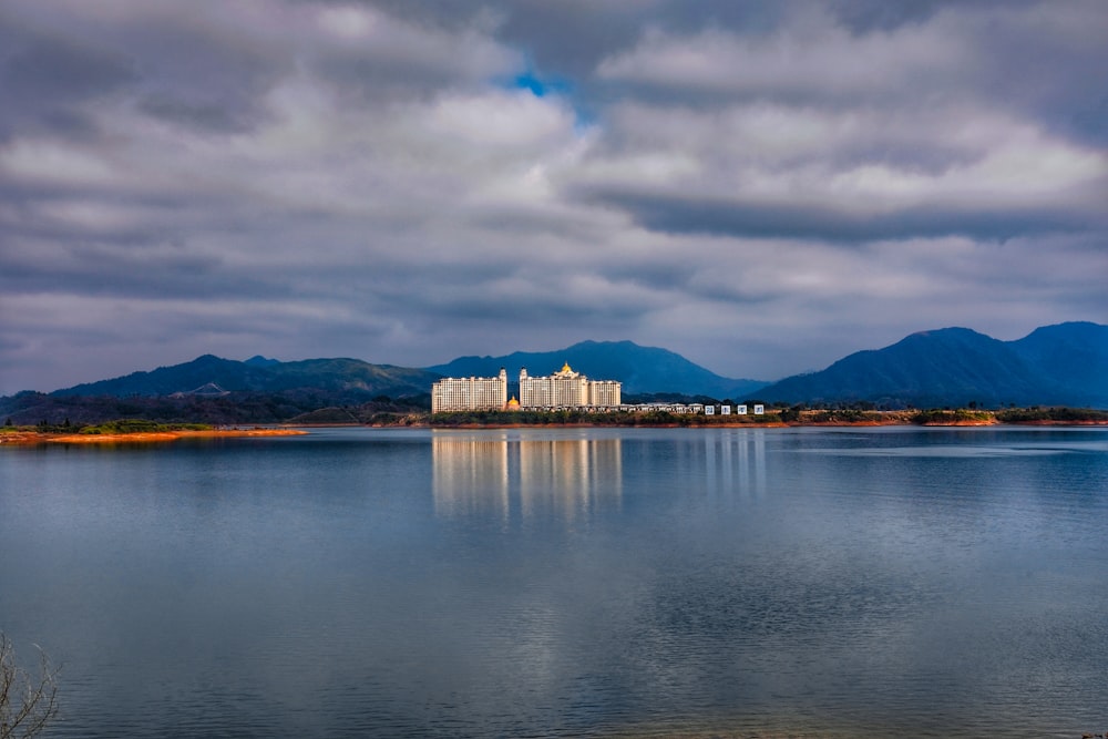 white and brown concrete building near body of water under cloudy sky during daytime