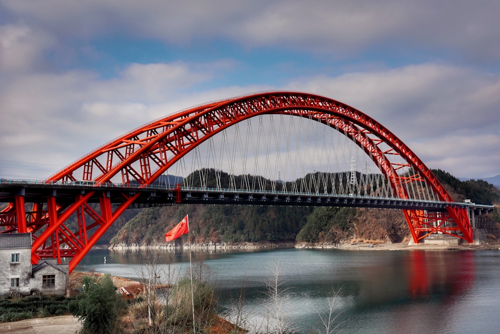 Puente de metal rojo sobre el río bajo el cielo nublado durante el día