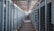 A long hallway in an industrial facility is filled with rows of server racks and electronic equipment. Metal frames and ducts run along the ceiling, and the space is brightly lit, emphasizing the orderly arrangement of the machinery.